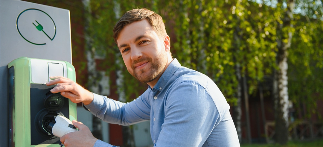 Chico cogiendo el cargador de un coche eléctrico