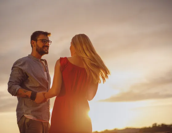 Pareja dándose las manos con el atardecer de fondo