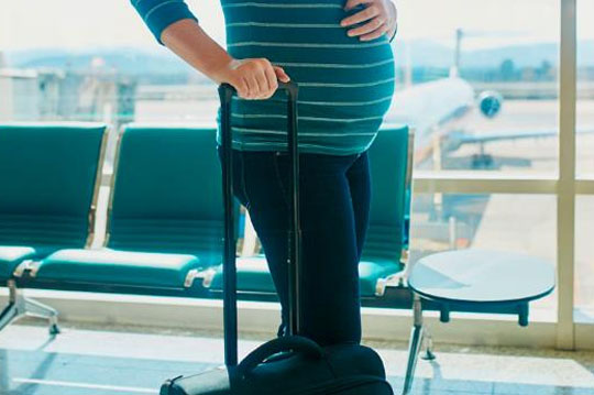 Mujer embarazada esperando el vuelo en un aeropuerto